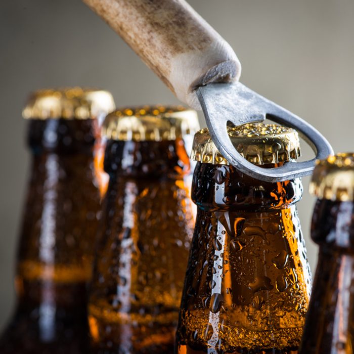 Brown ice cold beer bottles with water drops and old opener