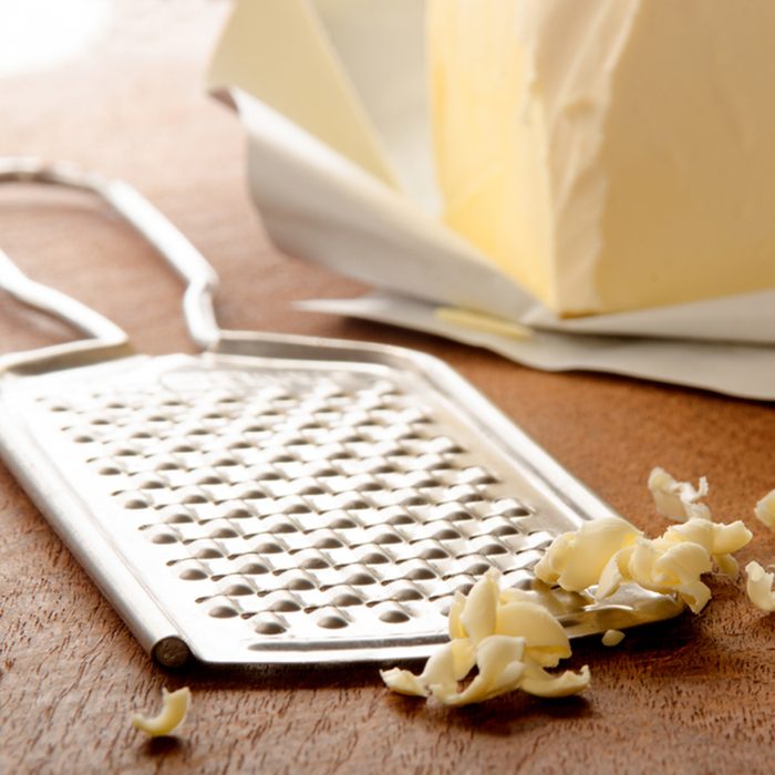 grated butter and grater on wooden board; Shutterstock ID 398422966