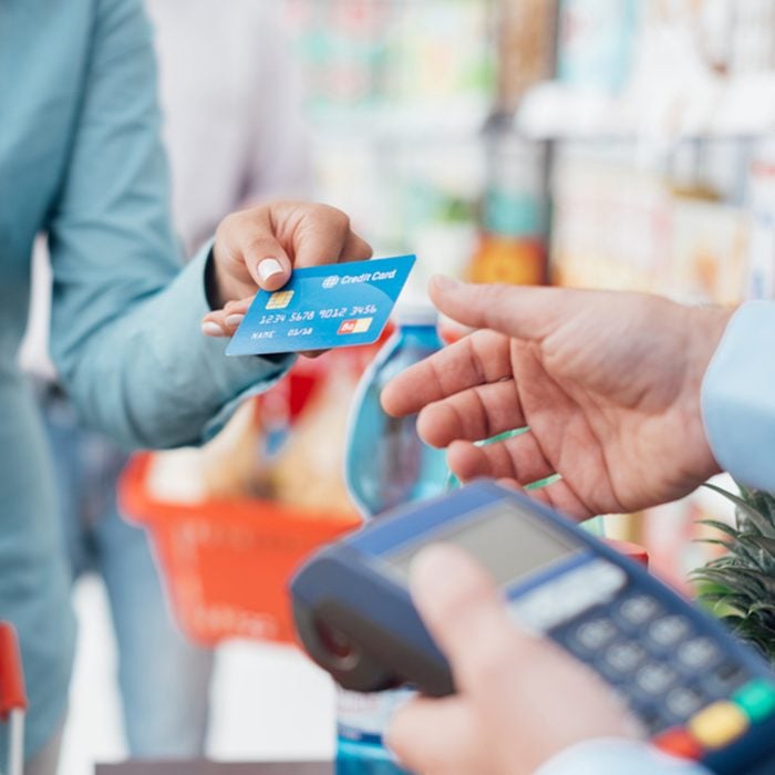 Woman at the supermarket checkout, she is paying using a credit card, shopping and retail concept; Shutterstock ID 503419588