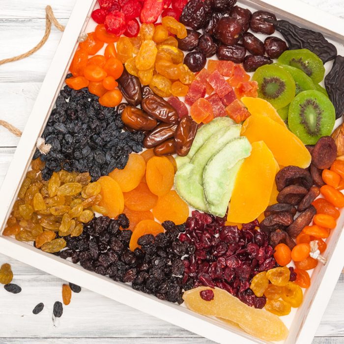 Mix of dried and sun-dried fruits, dried fruits in a wooden box on a white wooden background.