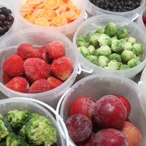 Frozen summer fruits and healthy vegetables in plastic containers