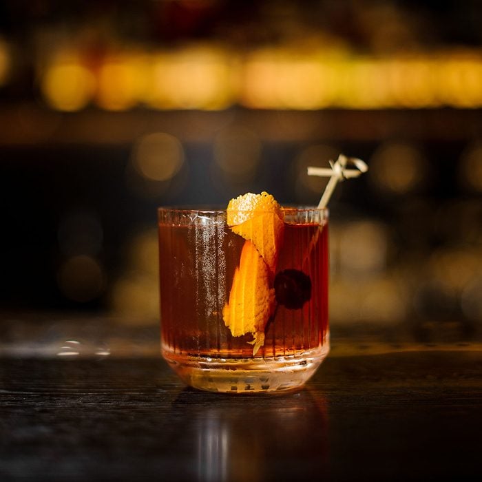 Glass of a Old Fashioned cocktail on the wooden bar counter on the blurred background