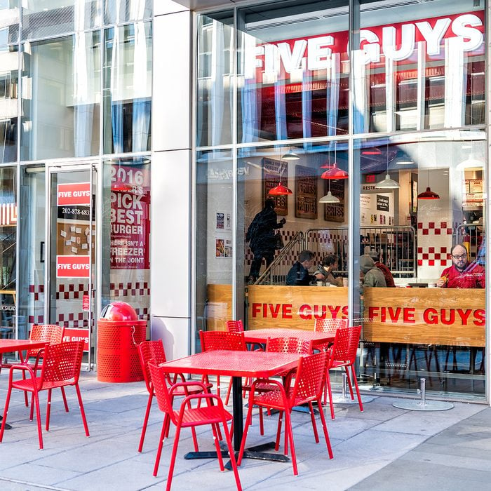 Five Guys restaurant, store burger chain entrance in District of Columbia with chairs, tables, outside, outdoor sitting area, people inside eating