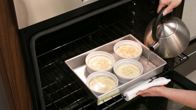 Pouring a water bath for custard cups in the oven