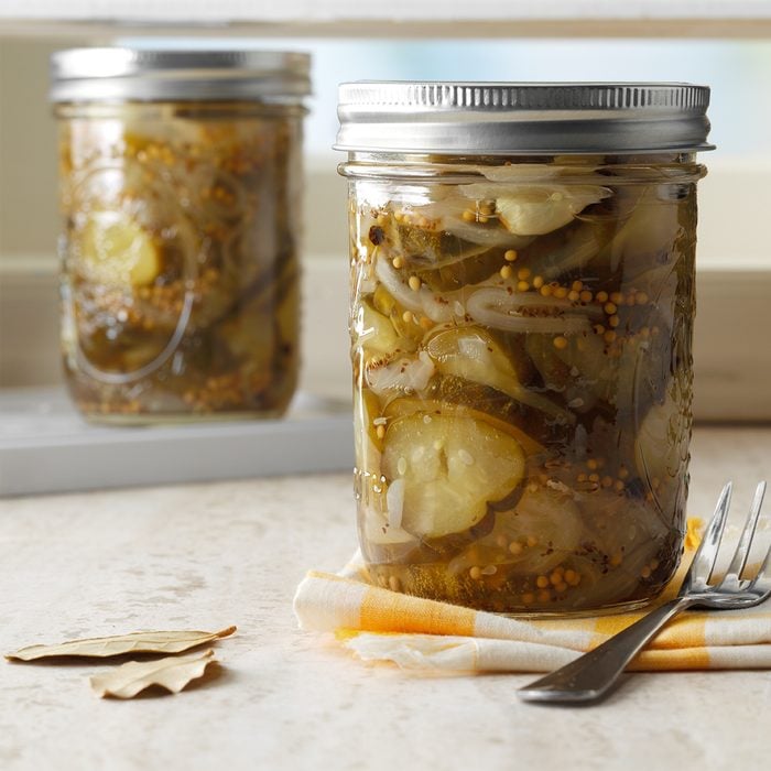 two jars of the best pickles recipe with a napkin, fork and bay leaves