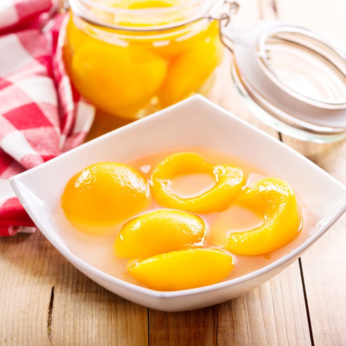 Canned peaches in a bowl on wooden table