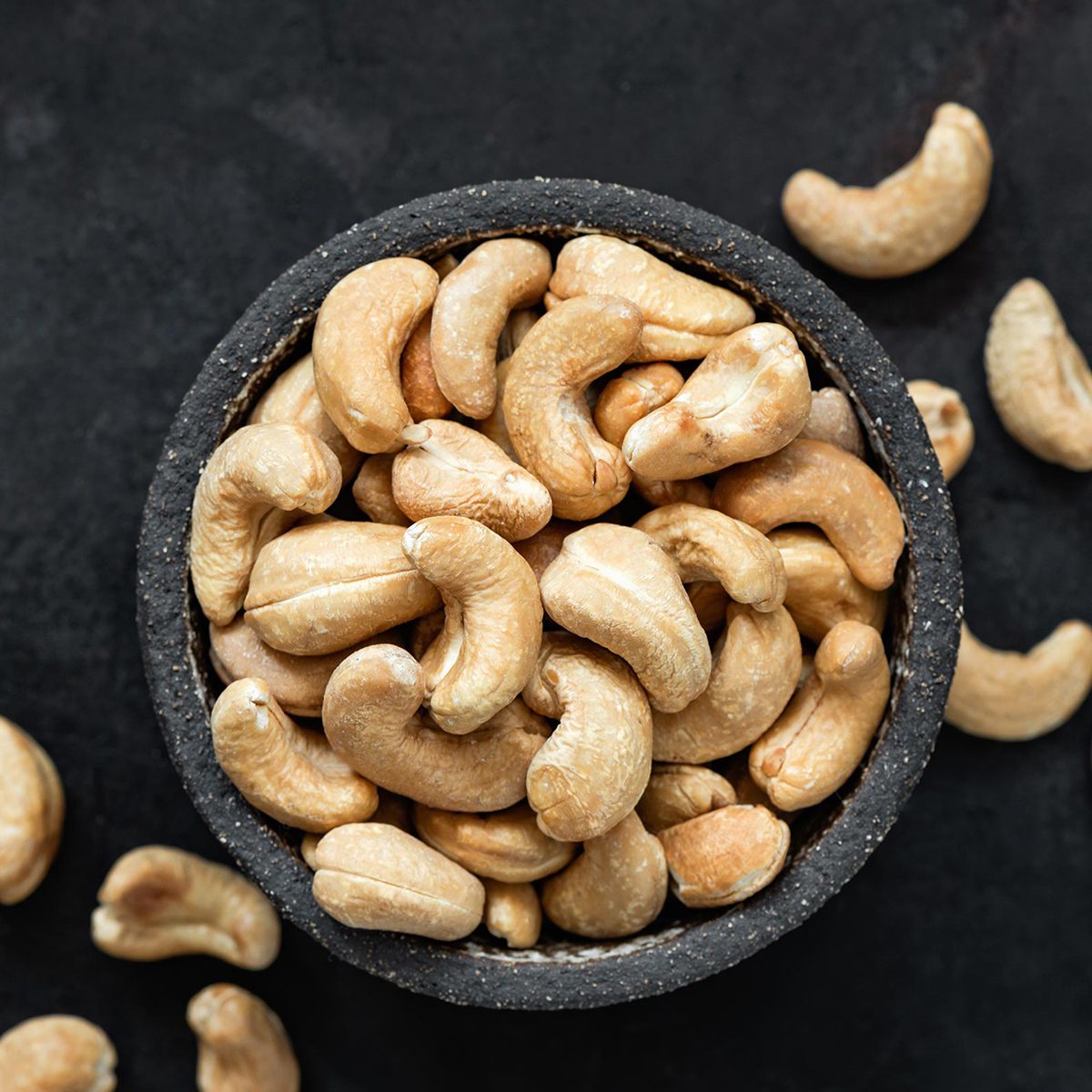 Cashew nuts in bowl on black background.