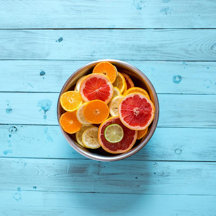 Mix of fresh ripe citrus fruits in a bowl in a centre of blue wooden background