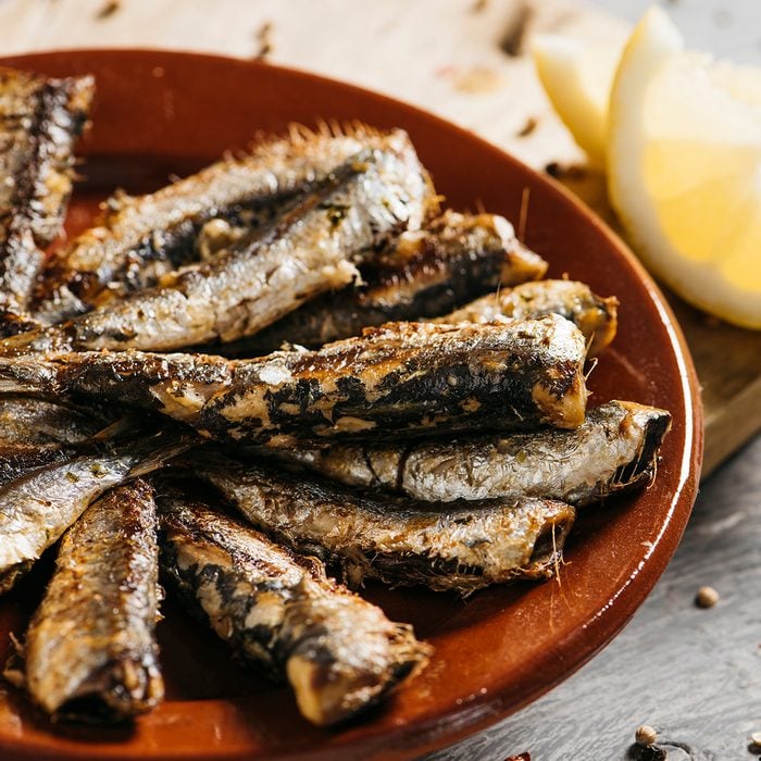 closeup of some spanish grilled sardines in a brown earthenware plate