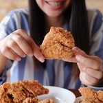 close up focus woman hand hold fried chicken for eat