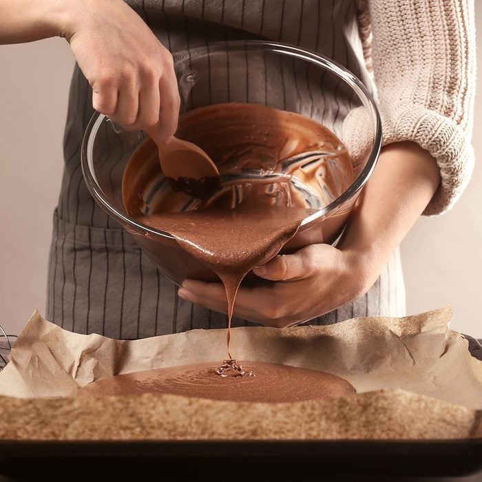 Woman pouring cacao liquid dough into baking tray