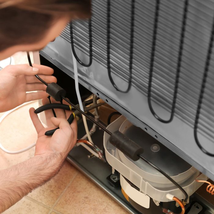 Male technician repairing refrigerator indoors; Shutterstock ID 1013281213