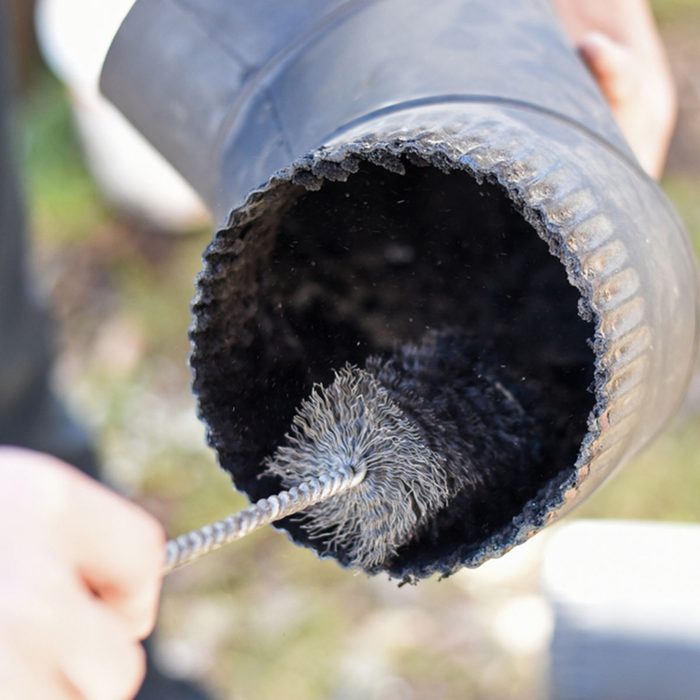 Man cleaning chimney pipe outside. Cleaning a wood burning stove. Chimney sweep cleaning; Shutterstock ID 1016950948; Job (TFH, TOH, RD, BNB, CWM, CM): Taste of Home