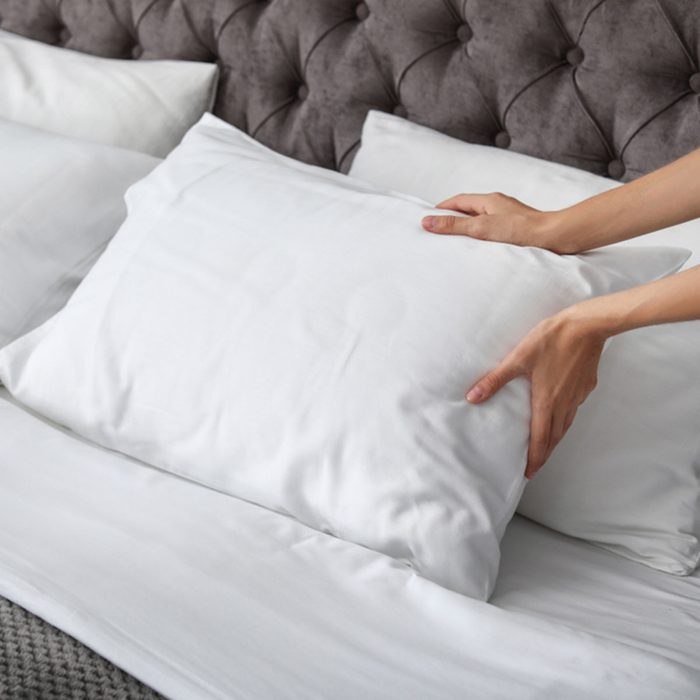 Young woman plumping white pillow on bed, closeup; Shutterstock ID 1149647606; Job (TFH, TOH, RD, BNB, CWM, CM): Taste of Home
