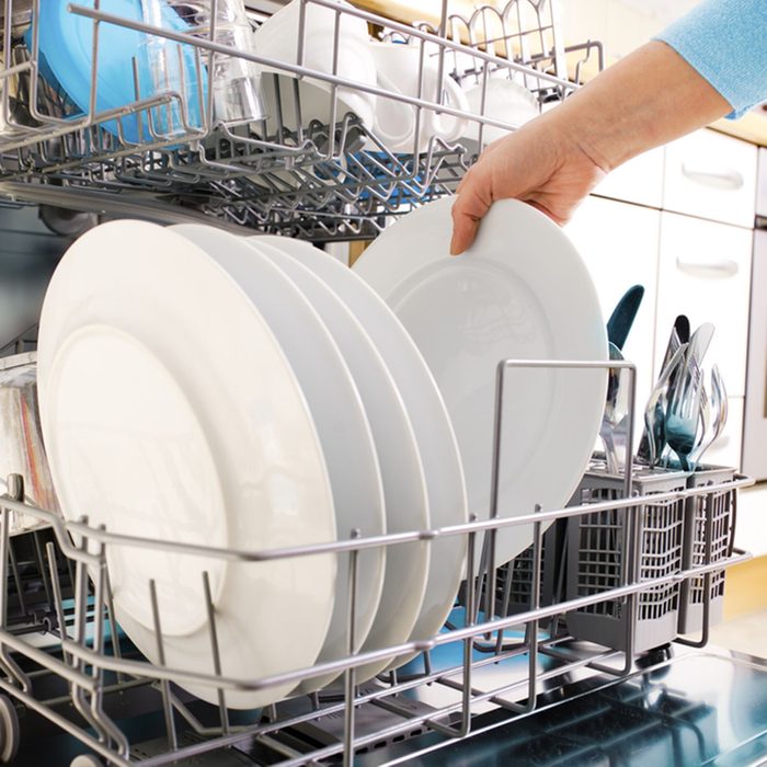 close-up of female hands loading dishes to the dishwasher; Shutterstock ID 53629048