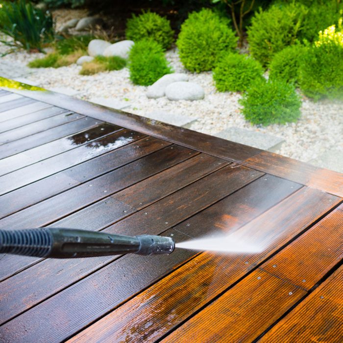 cleaning terrace with a power washer - high water pressure cleaner on wooden terrace surface; Shutterstock ID 553183696