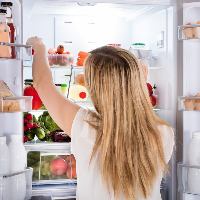 Rear View Of Young Woman Looking At Food In Open Refrigerator; Shutterstock ID 566230429