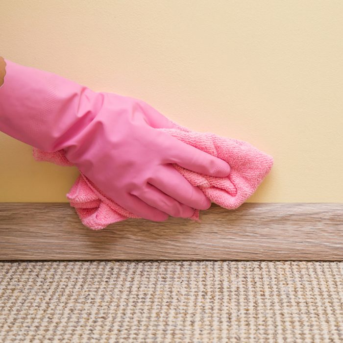 Hand in rubber protective glove with microfiber cloth cleaning baseboard on the floor from dust at the wall. Early spring cleaning or regular clean up. Maid cleans house.; Shutterstock ID 687988345; Job (TFH, TOH, RD, BNB, CWM, CM): Taste of Home