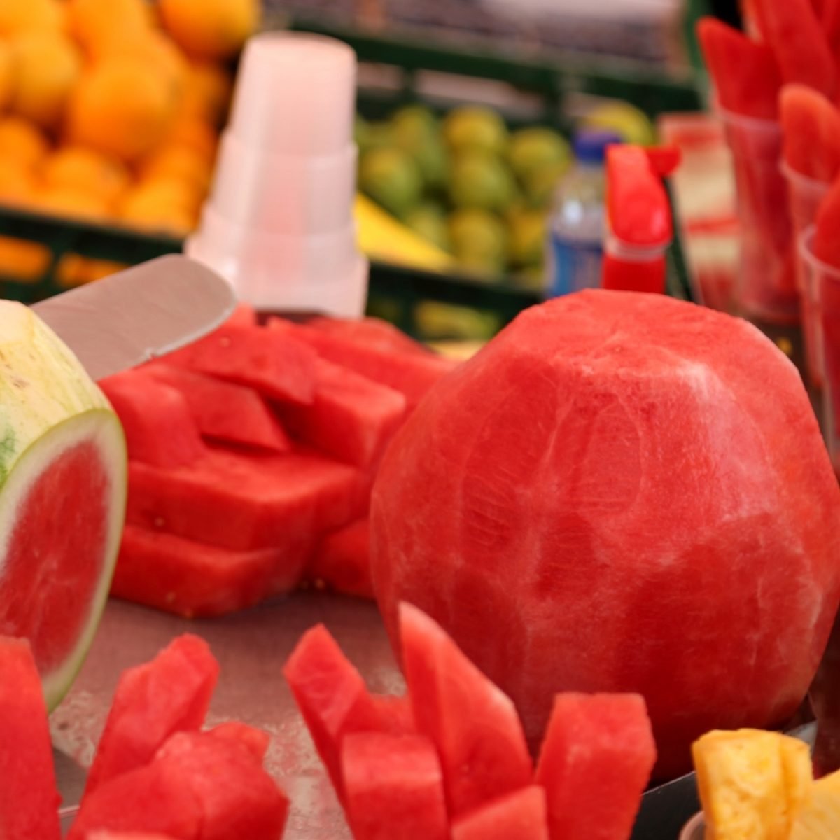 Man cuts the watermelon with a knife to prepare the fruit salad for sale