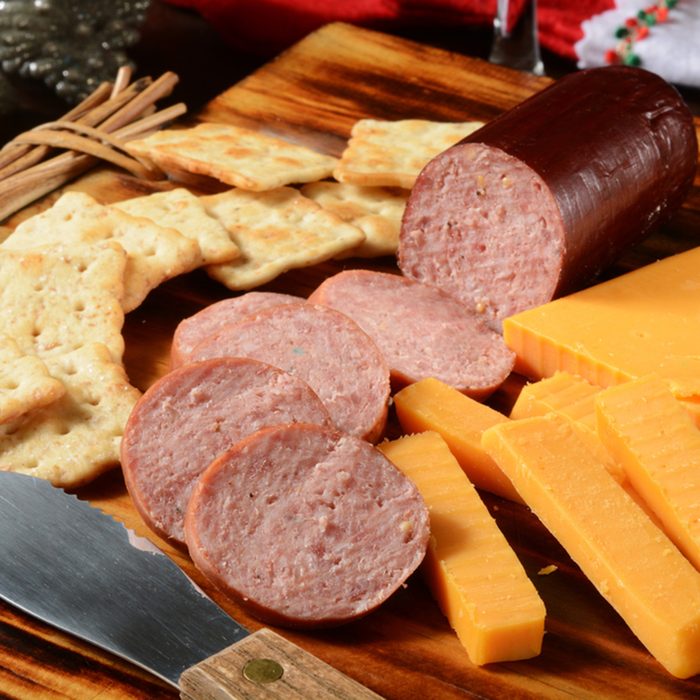 Sliced summer sausage with cheddar cheese and crackers on a holiday table