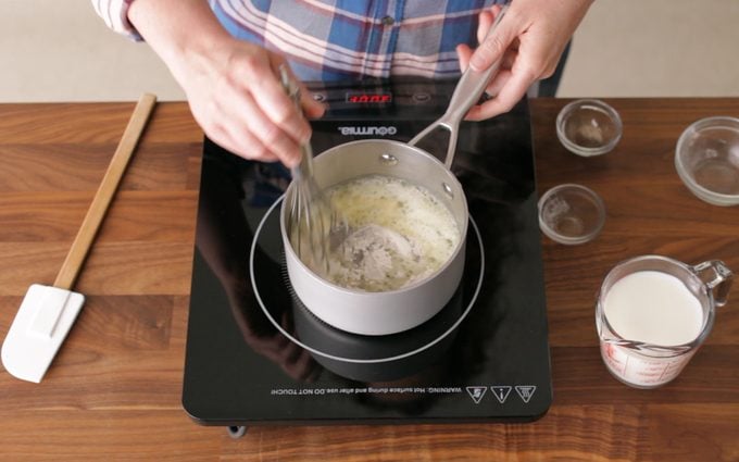 person mixing ingredients with a whisk in a sauce pan on a hot plate to Make A Roux