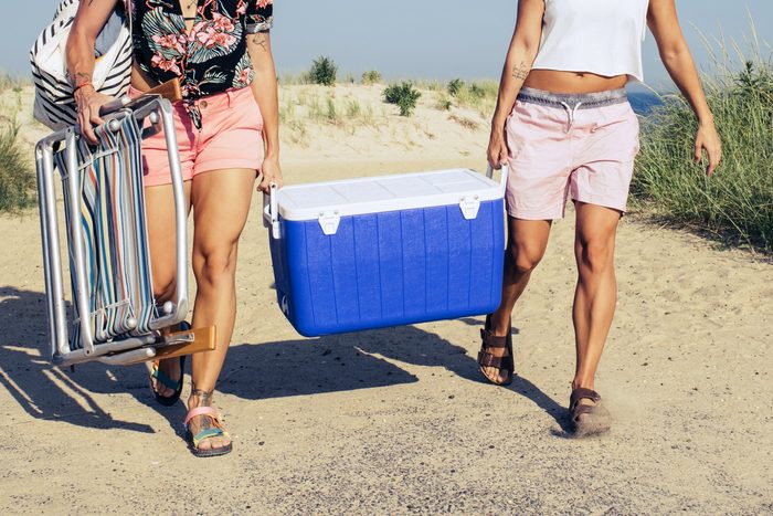 two women carrying a cooler to the beach