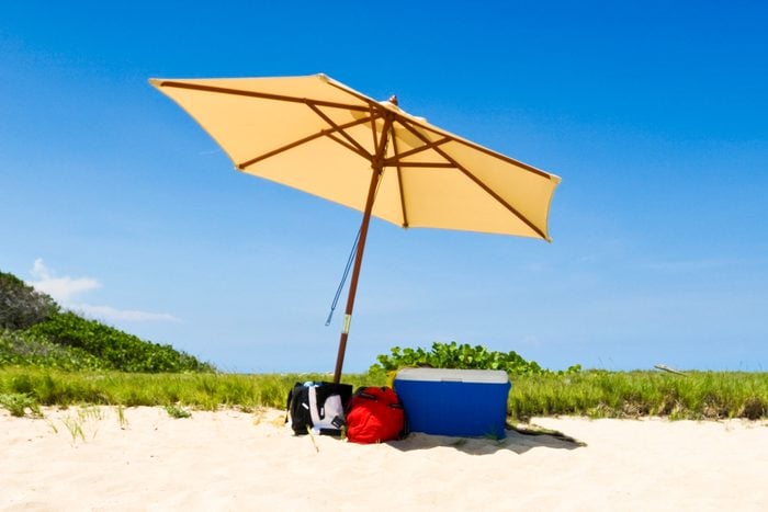 Cooler In The Shade under a yellow umbrella at the beach