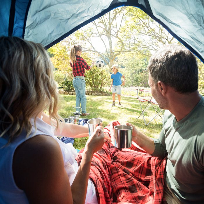 Rear view of couple having coffee and looking at kids playing outside the tent; Shutterstock ID 635870486; Job (TFH, TOH, RD, BNB, CWM, CM): TOH
