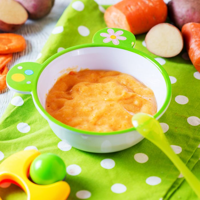 Food for kids, children's lure, organic puree from boiled potatoes and carrot in a bowl on a white rustic wooden background