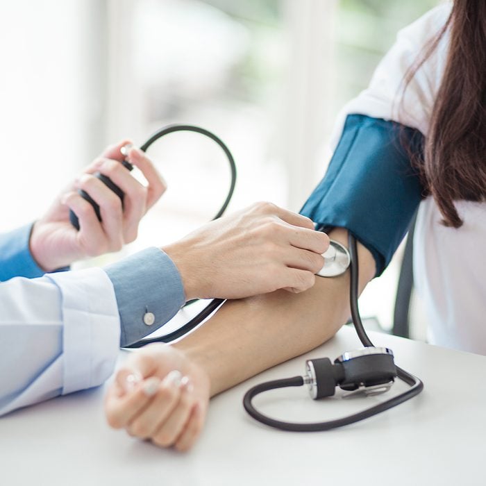 Doctor using sphygmomanometer with stethoscope checking blood pressure to a patient in the hospital.