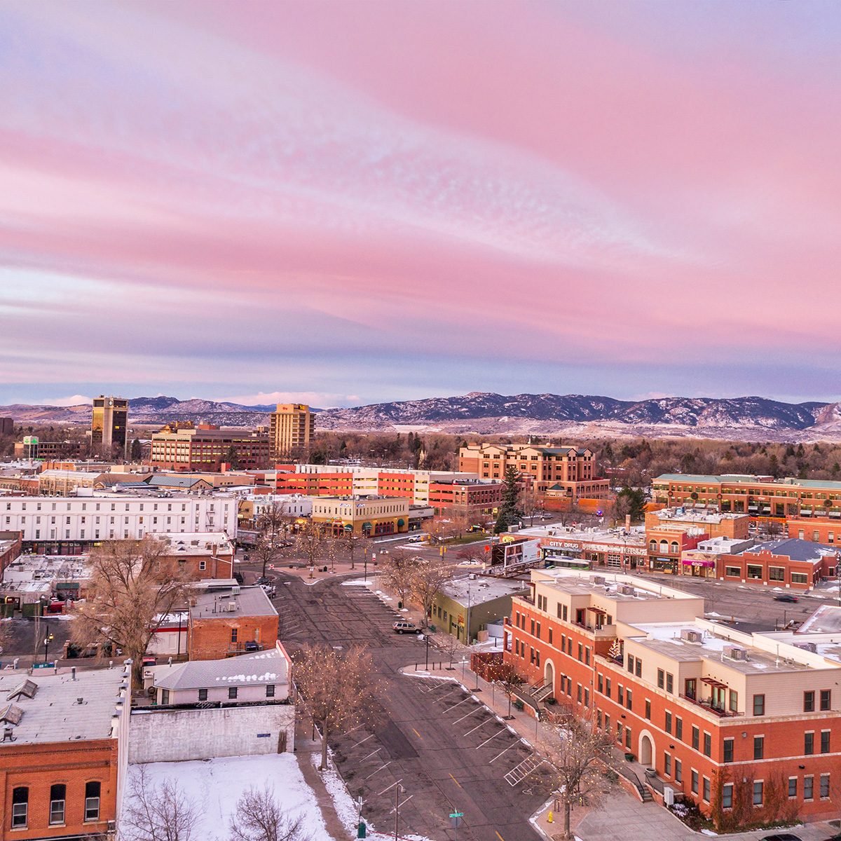Downtown of Fort Collins, Colorado at cold winter dawn - aerial view with holiday lights and Rocky Mountains in background.