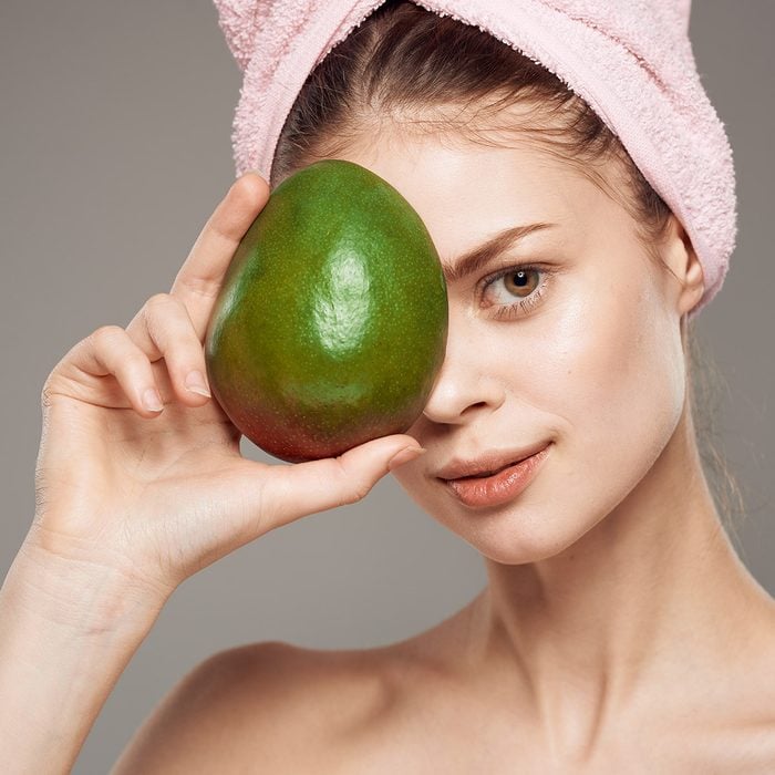 woman with green fruit, mango, clean skin, hair mask