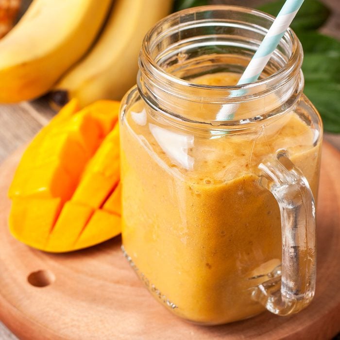 smoothie with tropical fruits: mango, banana, pineapple in a glass jar Mason on the old wooden background
