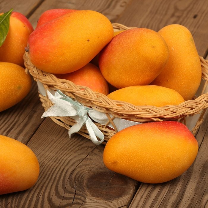 Ripe mango with mango leaf in wooden background.