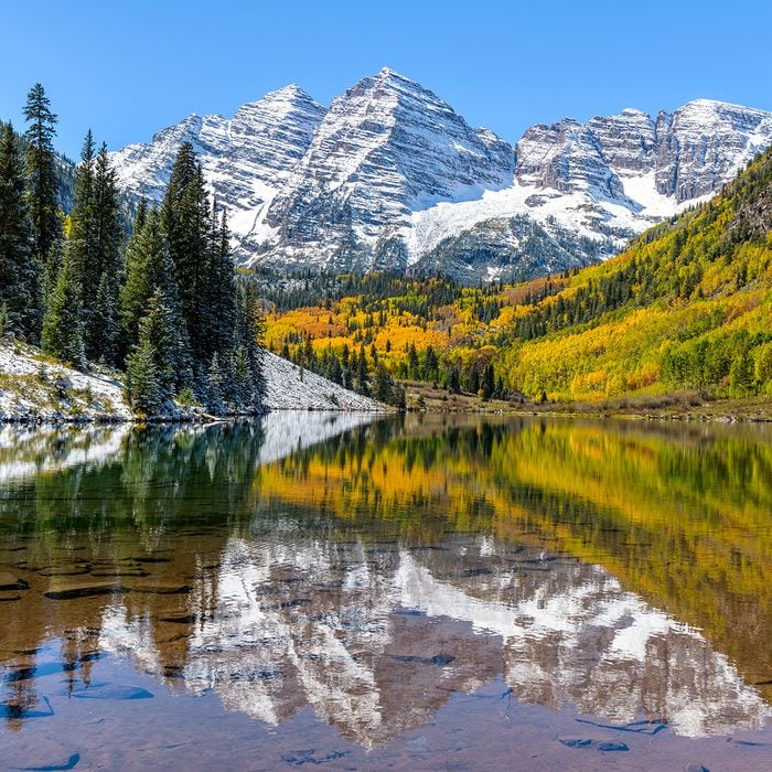 Maroon Bells and Maroon Lake - A wide-angle autumn midday view of snow coated Maroon Bells reflecting in crystal clear Maroon Lake, Aspen, Colorado