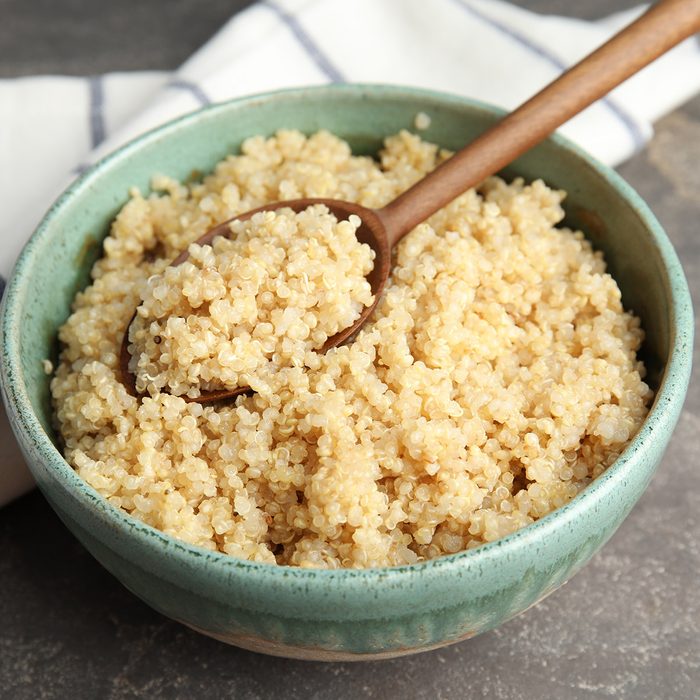 High-fiber food: Composition with cooked quinoa in bowl and wooden spoon on table