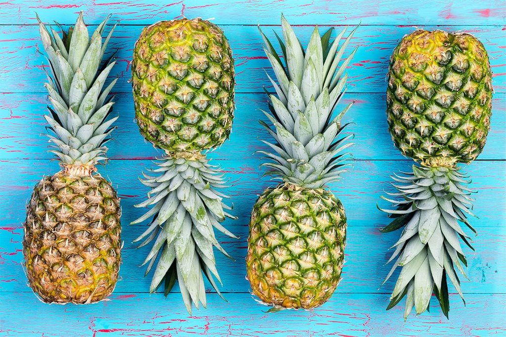 Four pineapple fruits arranged alternating next to each other on old blue crackled wooden market table; Shutterstock ID 549536092; Job (TFH, TOH, RD, BNB, CWM, CM): TOH