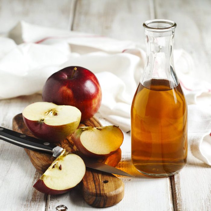 Jug of apple cider vinegar and sliced red apples