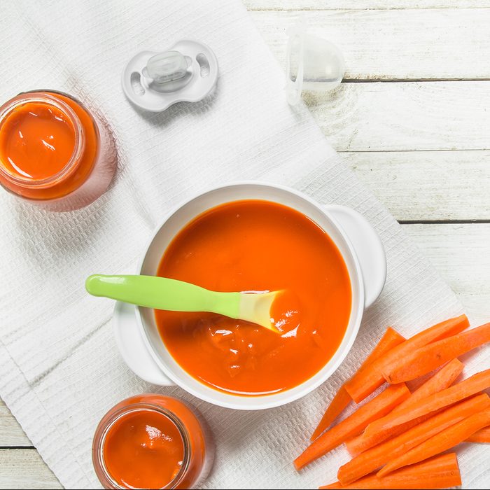 Baby food. Baby puree from fresh carrots with a spoon.