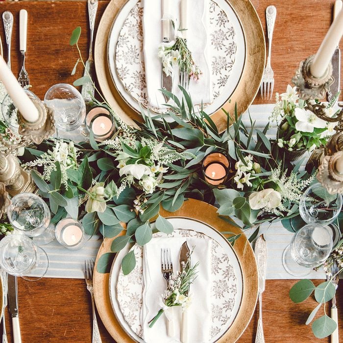 Aerial view of winter green garland on a wedding receptions head table with gold place setting and candelabra