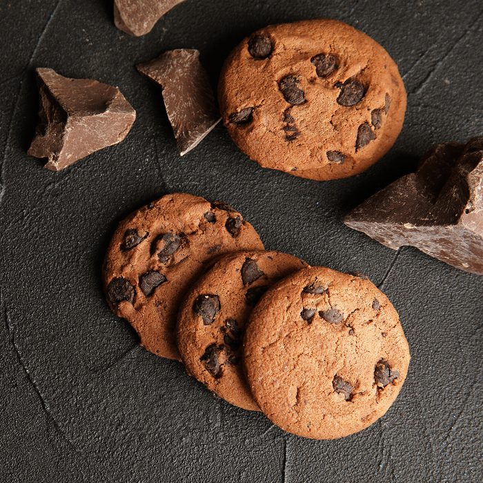 Tasty chocolate chip cookies on dark background, flat lay. 