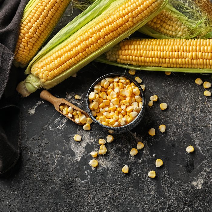 Composition with fresh corn cobs on dark background