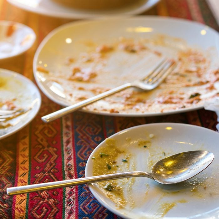 Empty dirty plates with spoon and forks on the table with a bright tablecloth