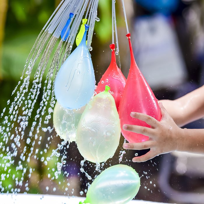 children holding colorful water balloons on his hand.