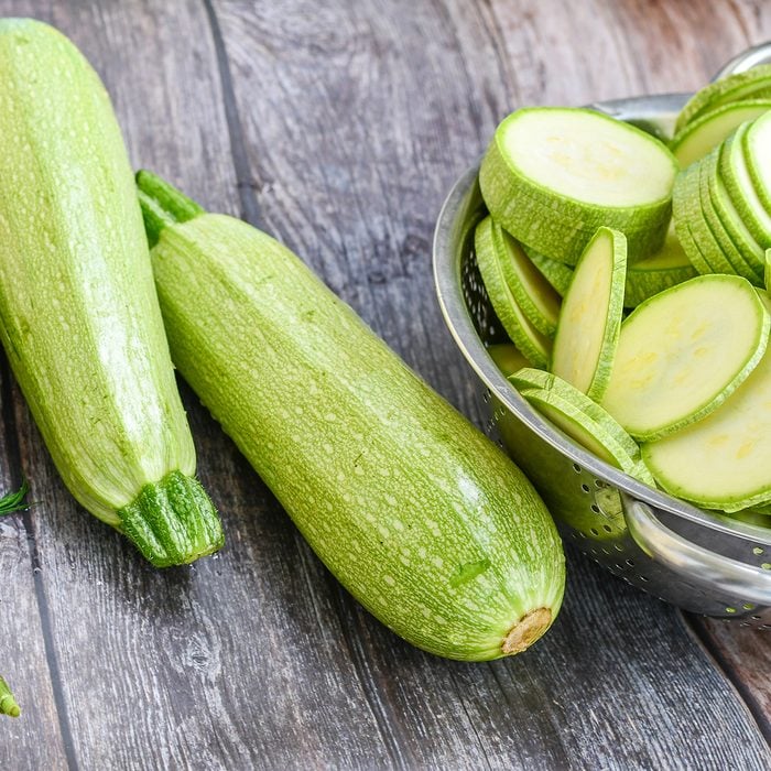 Fresh sliced raw bio zucchini and dill on wooden background.