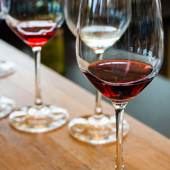 Detail of glasses with red wine samples, on wood counter.