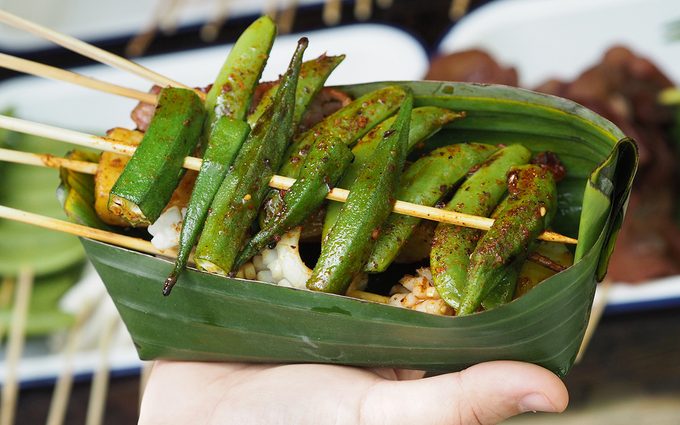 Close up Okra Vegetables and meats are grilled and pour with Hua Jiao Sichuan pepper in banana leaf bowl