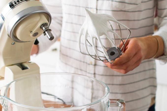 A person checking the stiff peaks of their homemade meringue.