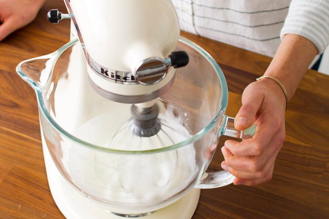 A close-up of a stand mixer beating egg whites in order to make meringue.