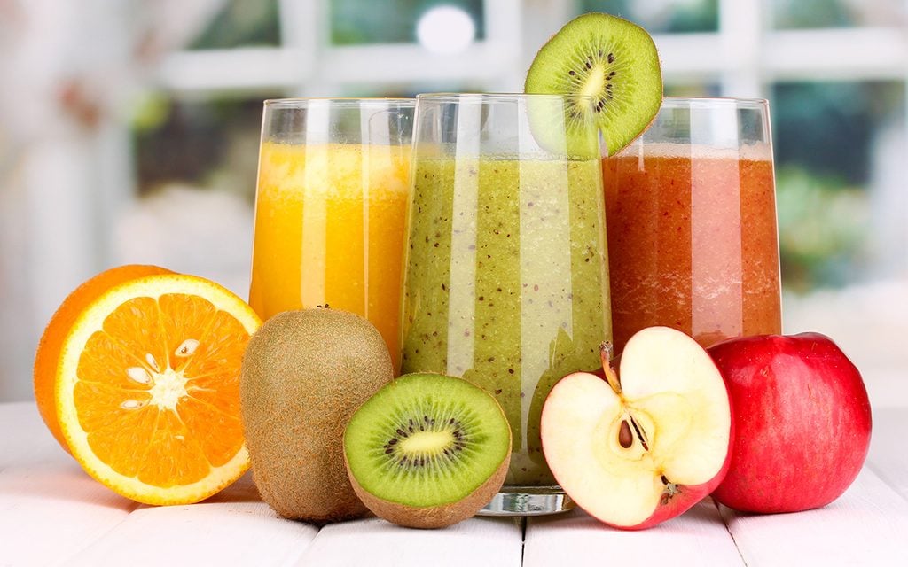 fresh fruit juices on wooden table, on window background